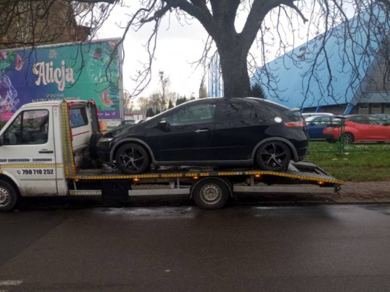 Transport uszkodzonego czarnego samochodu osobowego na lawecie na Śląsku